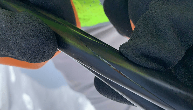 A black electrical cable showing a crack in the outer cable jacket.