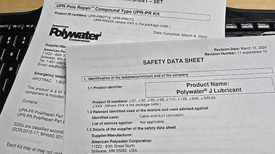 Two safety data sheet packets piled upon a black computer keyboard.